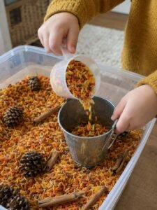 Child's hands pouring rice into a bucket 